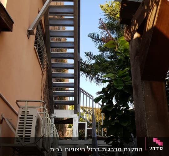 גרם מדרגות חיצוני ממתכת ומעקות ברזל לצד קיר מבנה